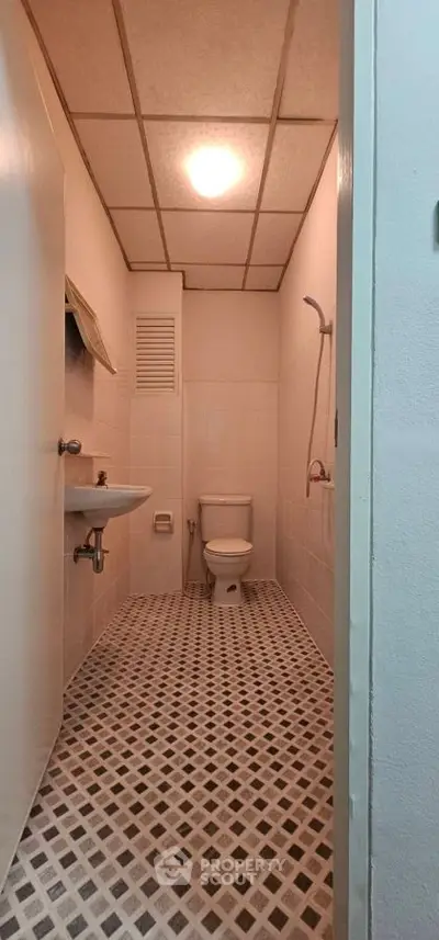 Compact bathroom with modern fixtures and geometric floor tiles.