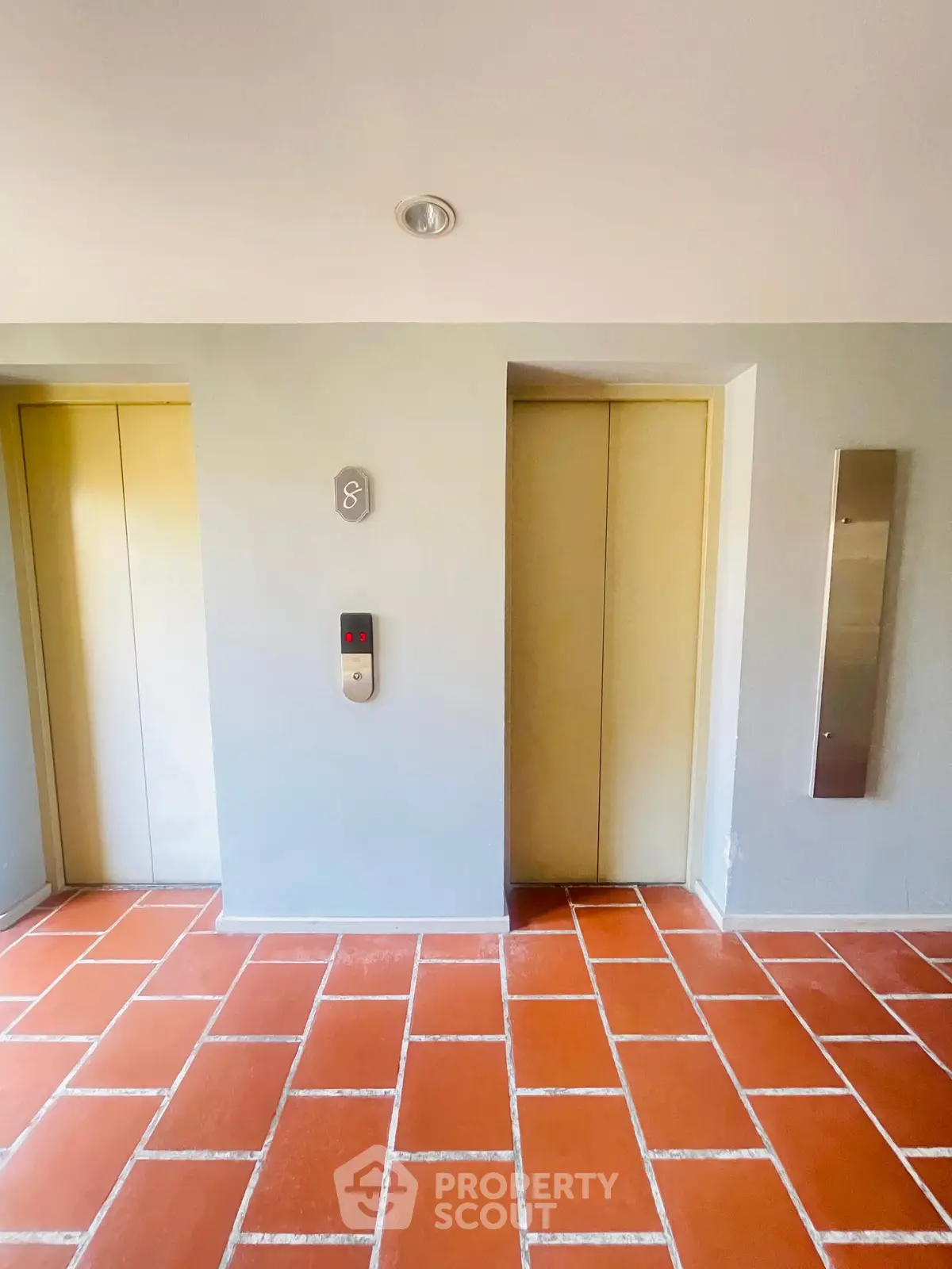 Modern building elevator lobby with terracotta tile flooring and sleek design.