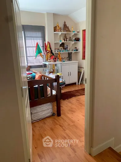Cozy bedroom with wooden flooring and decorative shelves, perfect for a peaceful retreat.