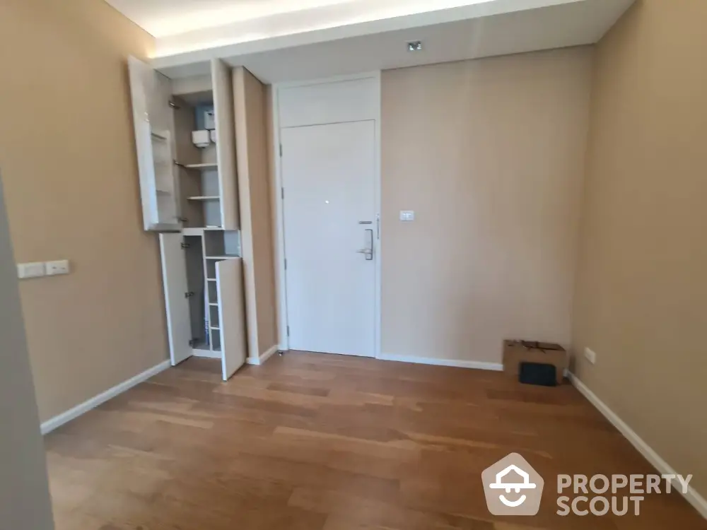 Spacious empty room with wooden flooring and built-in storage