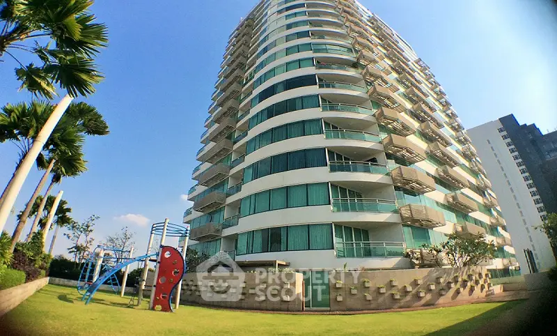 Modern high-rise building with lush garden and playground, ideal for family living.