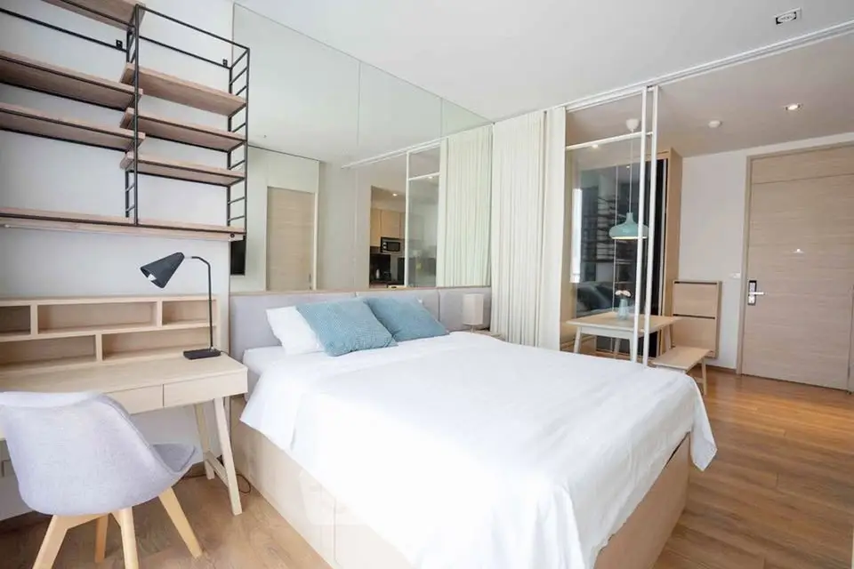 Modern bedroom with stylish decor, featuring a cozy bed, study desk, and elegant shelving.