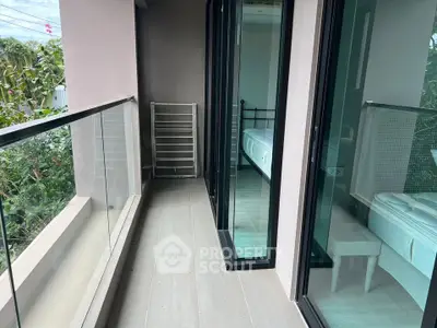 Spacious balcony with glass railing and garden view, adjacent to modern bedroom.