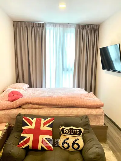 Cozy bedroom with stylish decor and natural light, featuring a comfortable bed and modern TV setup.