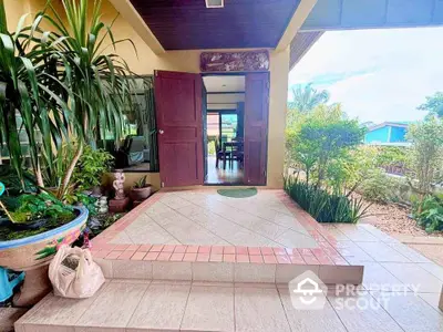 Charming entrance with lush greenery and inviting open doors