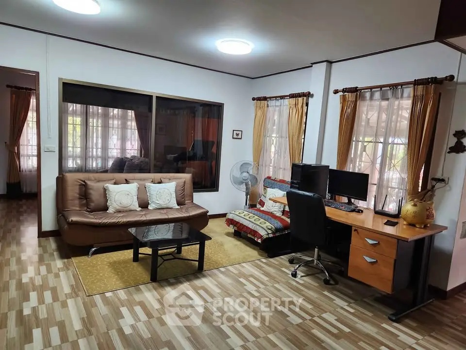 Spacious living room with cozy seating and home office setup, perfect for modern living.