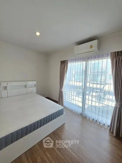 Spacious bedroom with large window and modern decor in a bright apartment.