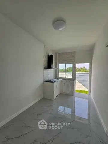 Bright kitchen with sleek white cabinetry and marble flooring, featuring a large window with a scenic view.