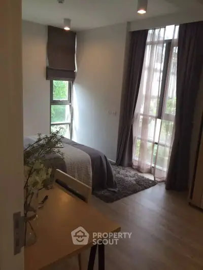 Cozy bedroom with large windows and modern decor in a stylish apartment.