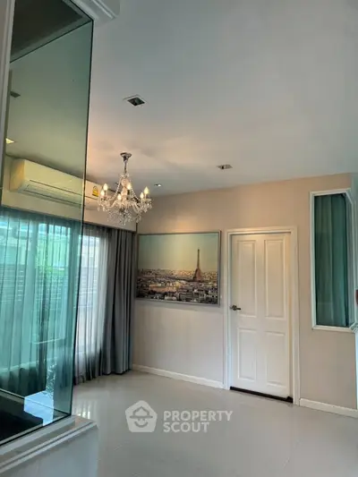 Elegant living room with chandelier and large window, featuring a Paris-themed wall art.