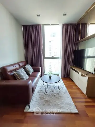 Modern living room with leather sofa and large TV, featuring floor-to-ceiling windows and elegant decor.