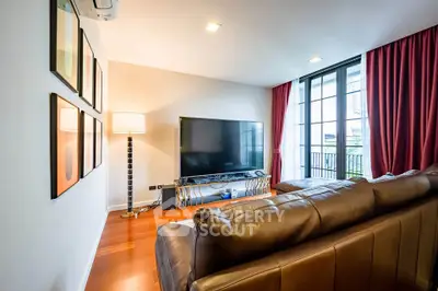 Spacious living room with modern decor and large TV, featuring floor-to-ceiling windows and elegant curtains.