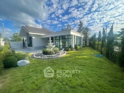 Stunning modern home with lush garden and elegant fountain under a vibrant sky.