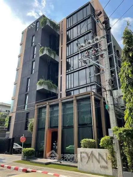 Modern multi-story building with sleek design and lush greenery in urban setting.