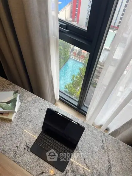Modern workspace with a stunning pool view from a high-rise apartment window.