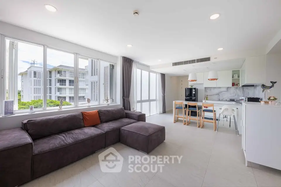 Spacious modern living room with open kitchen and large windows in a luxury apartment.