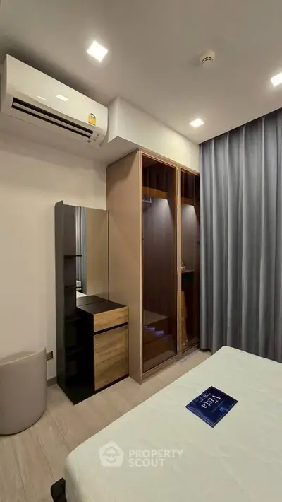 Modern bedroom with sleek wardrobe and air conditioning in a stylish apartment.