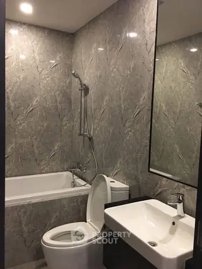 Modern bathroom with marble walls, bathtub, and sleek fixtures.