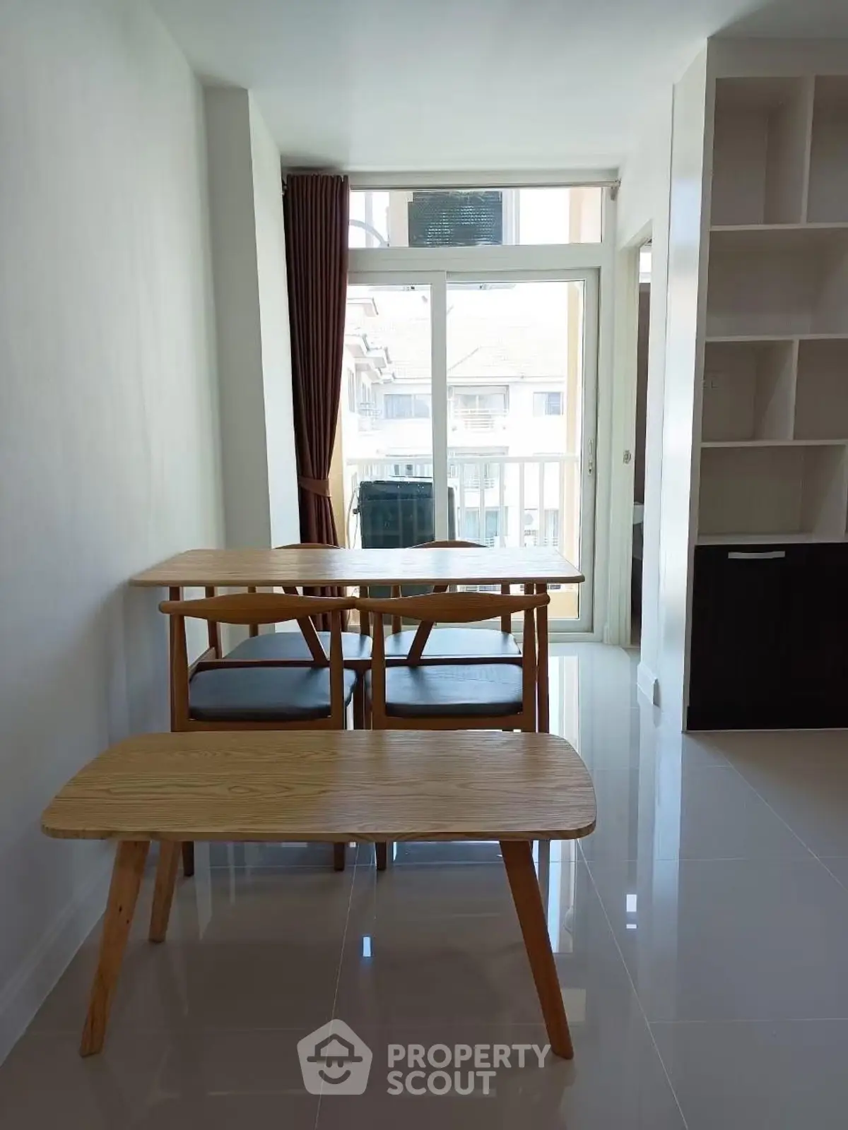Bright dining area with modern wooden table and chairs, large window, and built-in shelving.