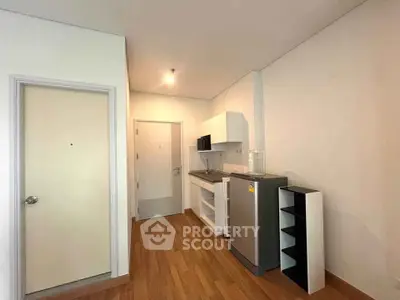 Modern compact kitchen with sleek appliances and wooden flooring in a cozy apartment.