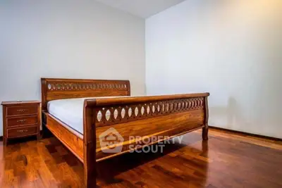 Spacious bedroom with elegant wooden bed and hardwood flooring