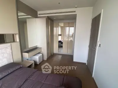 Modern bedroom with sleek design and mirrored wardrobe in a stylish apartment.