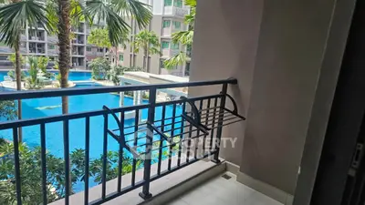 Charming balcony overlooking a luxurious pool with lush greenery in a modern residential complex.
