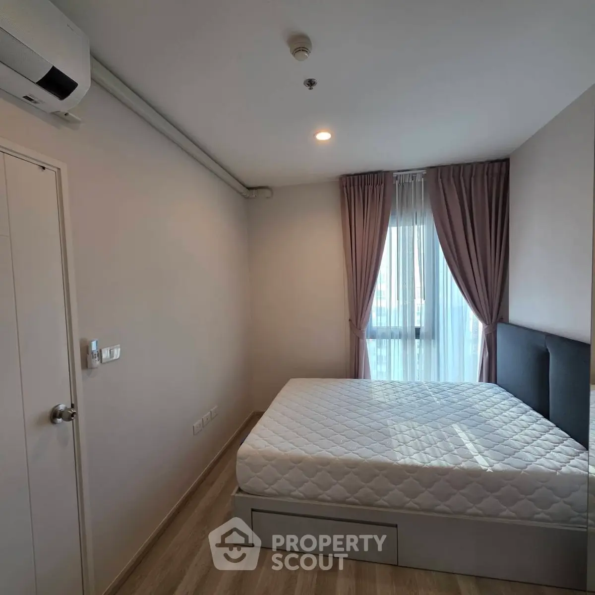 Cozy bedroom with natural light, featuring a comfortable bed and elegant curtains, perfect for relaxation.