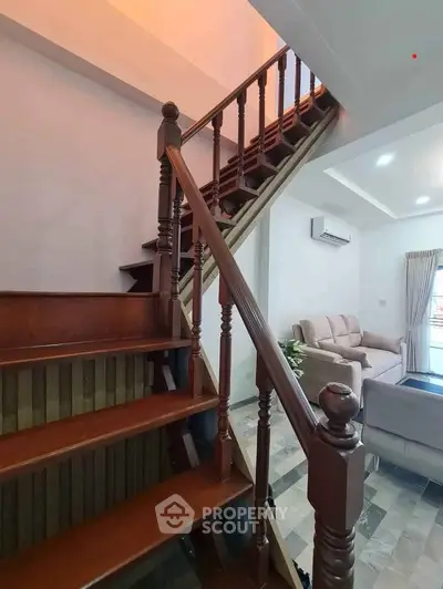 Charming wooden staircase leading to a cozy living room with modern decor and air conditioning.
