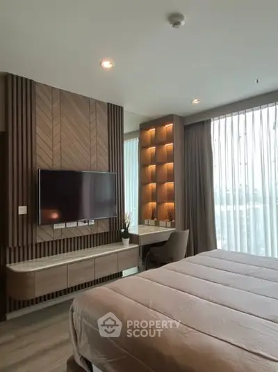 Modern bedroom with stylish wood paneling and large TV, featuring natural light and elegant decor.