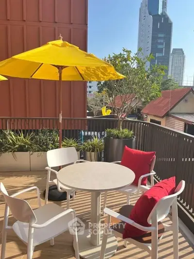 Charming balcony with city view, modern furniture, and vibrant yellow umbrella.