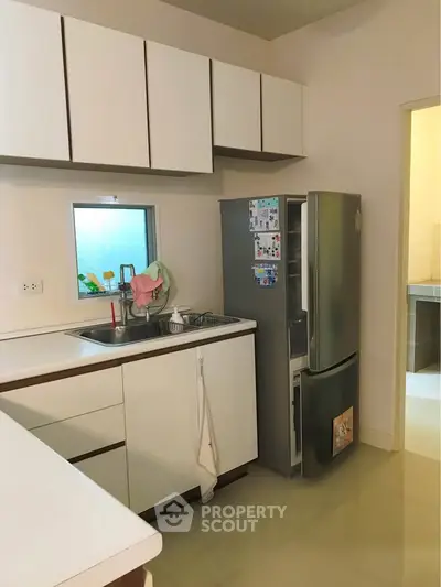 Modern kitchen with sleek cabinets and stainless steel fridge in cozy apartment.