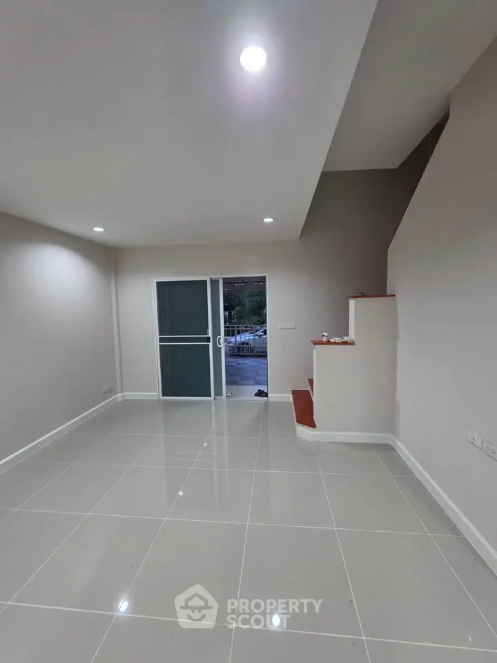 Spacious modern living room with sleek tile flooring and staircase, perfect for contemporary living.