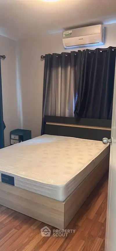Cozy bedroom with air conditioning and wooden flooring, perfect for restful nights.