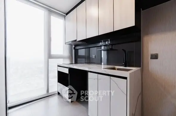 Modern kitchen with sleek cabinetry and marble countertops in high-rise apartment.