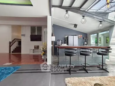 Modern open-plan living area with stylish kitchen and bar seating, featuring sleek design and ample natural light.