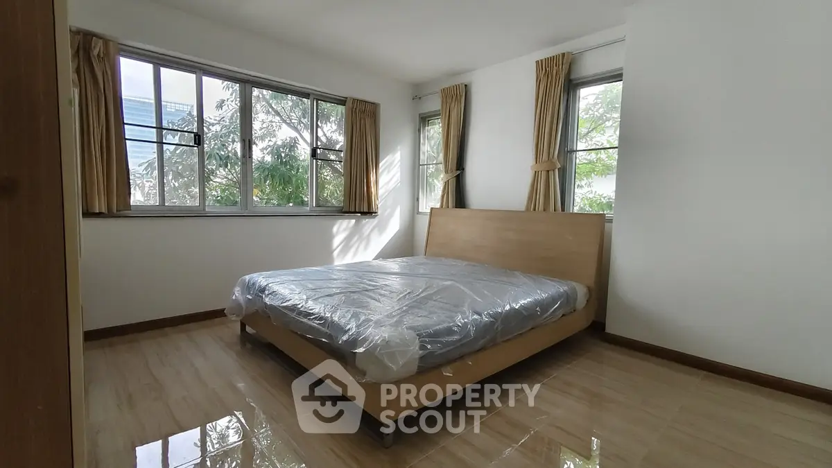 Spacious bedroom with large windows and natural light in modern apartment