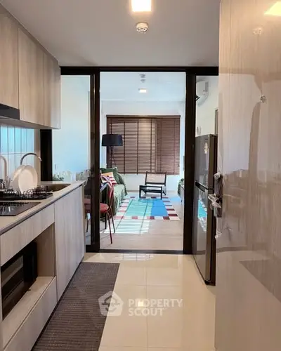 Modern kitchen with open layout leading to stylish living room with natural light.