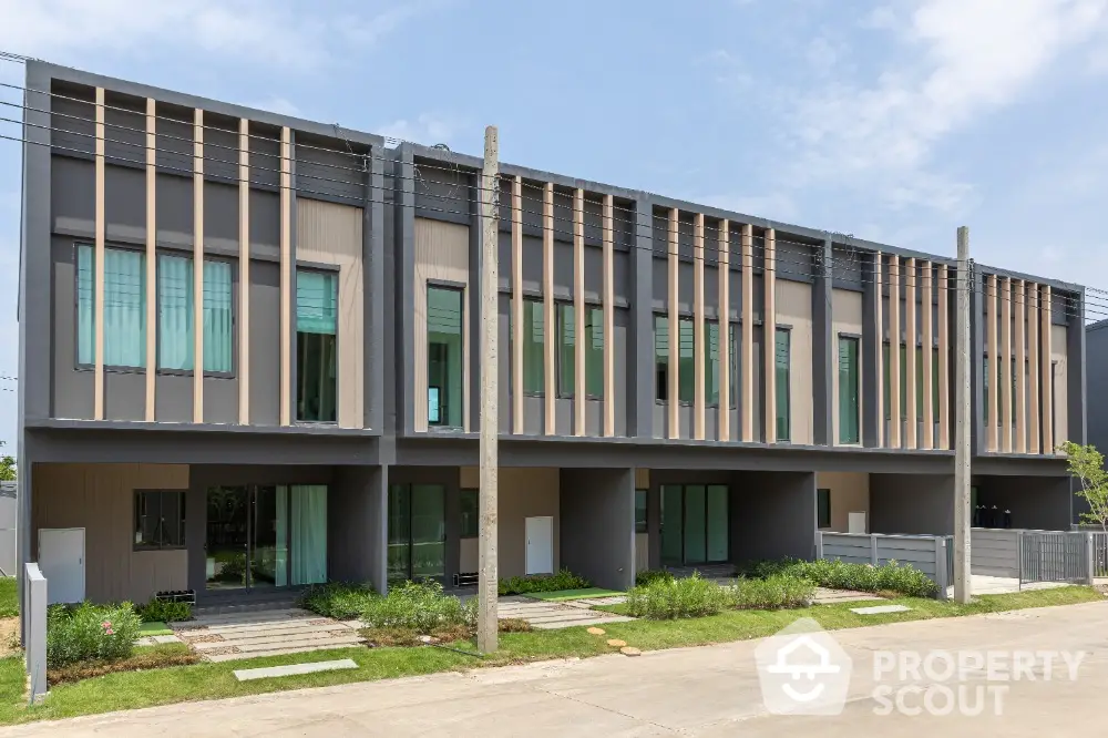 Modern townhouse exterior with sleek design and large windows in a suburban neighborhood.