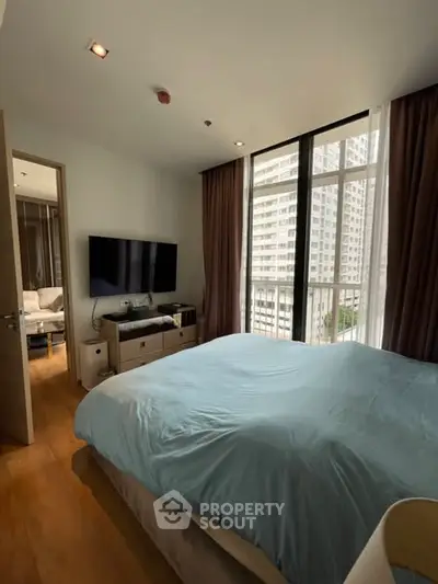 Spacious bedroom with large windows and city view in modern apartment