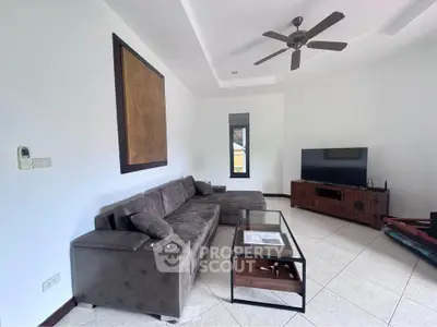 Spacious living room with modern sofa, ceiling fan, and entertainment center.