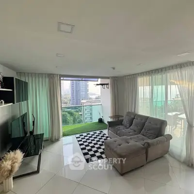 Spacious living room with modern decor and large windows offering a stunning city view, perfect for relaxation.