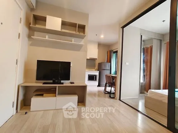 Modern apartment interior with open living room and kitchen, featuring sleek furniture and wooden flooring.