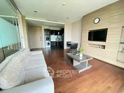 Modern living room with open kitchen, wooden flooring, and stylish furniture in a contemporary apartment.
