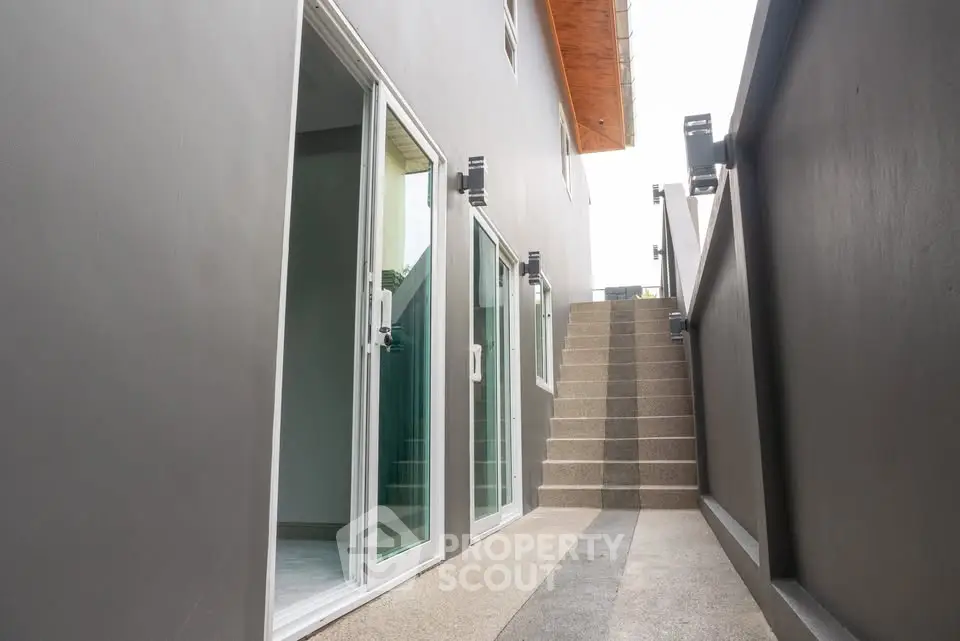 Modern exterior with sleek staircase and glass doors leading to a stylish home entrance.