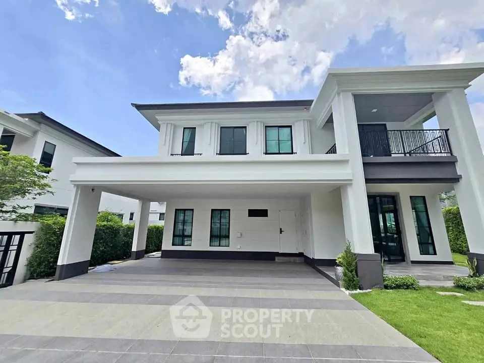 Elegant modern two-story house with spacious driveway and lush green lawn under a clear blue sky.