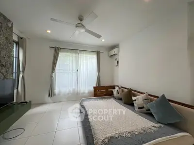 Spacious living room with modern decor and natural light, featuring a cozy seating area and ceiling fan.