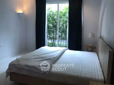 Cozy bedroom with large window and garden view, perfect for relaxation.
