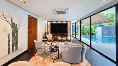 Luxurious living room with pool view, modern furniture, and large glass doors opening to a serene outdoor space.