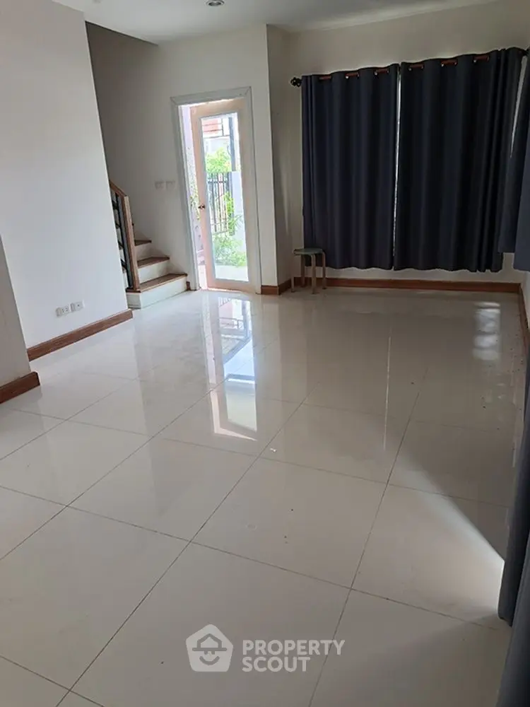 Spacious living room with glossy tiled floors and large window for natural light.